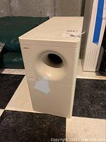 White Bose Acoustimass series III subwoofer showing the circular bass port on the front and scuff mark on lower front area.