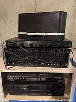 Shelf view showing Sirius XM docking speaker atop ADC equalizer, with Magnavox DVD player and Sony cassette deck below