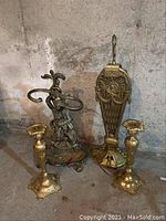 Brass fireplace accessories including two candle stick holders, a fireplace tool holder, and a fireplace fan.