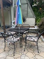 Overall view of table, chairs and umbrella on stone patio