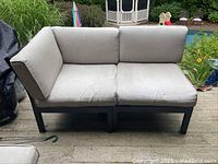 Front view of outdoor loveseat showing beige cushions and metal frame with rust.