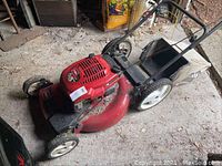 Full side and top view of the Toro lawn mower showing red deck, black handles and attached leaf bag.