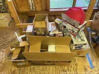 Boxes and loose car parts arranged on wooden floor showing the lot contents