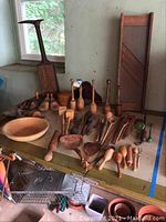 Overview of table with assortment of wooden kitchen utensils and shoemaker tools.