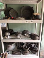 Three shelves with assorted bakeware, including various pans and kitchen utensils.