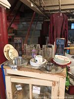 Overview of bottles including vintage boxed Davidson bottle, clear glass and plastic bottles, children's dishware with Looney Tunes characters, and metal inkwell on table.