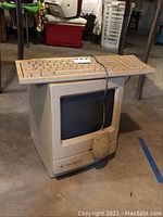 Full shot of the Macintosh Classic with keyboard sitting on top and mouse draped over front.