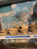 Photo showing top shelf with various medium to large yellowware bowls and molds including fluted molds and mixing bowls