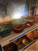 Wide view of assortment showing variety of glass bowls and plates on upper shelving and stoneware bowls on lower shelf