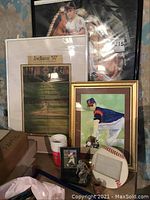 Photo showing framed 1997 Indians championship poster, framed watercolor painting of Cleveland Indians player, souvenir cup, glass figurine, baseball card display, and large decorative baseball item.