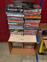 Stack of DVDs and boxed sets including Band of Brothers on top with various movie titles below.