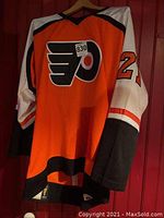 Full view of the orange, white, and black Philadelphia Flyers jersey with large Flyers logo and number patch on front.