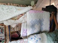 Quilts hanging on wooden drying rack showing pastel quilts with geometric and floral patterns