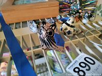 Front view photo showing hand-painted animal figurines on a display rack, including an owl and multiple bird figures.