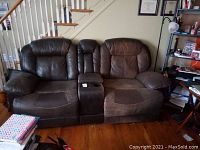 Full front view of the reclining loveseat showing seating, armrests, and center console with cup holders.