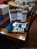 Front view of two Allen Iverson bobbleheads boxed, one Donovan McNabb bobblehead boxed, and two folded Philadelphia Eagles towels on a wooden table.