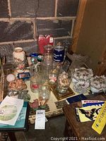 Overview of glass candle holders, vases, candy bowls, paperweights, and the card table surface with various items.