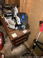 Delta 10 inch compound miter saw MS250 placed on a wooden table, showing the saw motor, blade cover, and part of the handle.