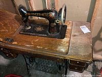 Side view of vintage Singer sewing machine mounted on wooden table showing wear and integrated pedal system.