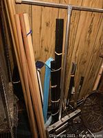 Flag poles and curtain rods in various sizes and materials leaning against a wall