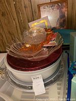 Plastic platters, bowls, and trays stacked with wall art in background.