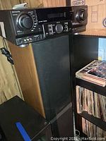 Aiwa AV S17 stereo receiver on top of a Technics SB W33 floor speaker, showing the front of the receiver and part of the speaker's wooden side and black grille.