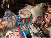 Photo showing crafting supplies including plastic canvas, foam shapes, plastic bucket, and various small items along with Howard Stern media and books stacked in background