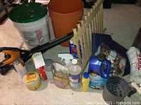 Full view showing the electric blower, wooden rack, white hangers, and assorted cleaning bottles and cans.