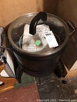 Black Butterball electric turkey roaster with glass lid and instruction booklet inside, shown from above.