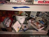 Overview of crafting supplies placed on bottom shelf including books, discs, and a ceramic container