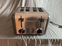 Front view of stainless steel toaster with 4 slots, dual lever and dial controls, showing wear.