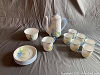 Full set displayed showing teapot, 6 teacups, 6 tea plates stacked, and creamer cup on cloth background