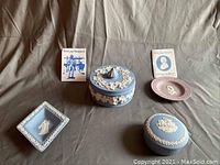 Photo of four Wedgwood bone china decorative pieces arranged with two Wedgwood informational pamphlets on a gray background