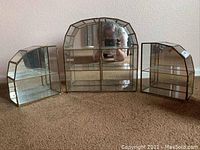 Full view of three stained glass display cases with brass accents and mirrored backs arranged side by side on carpet.