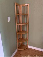 Front view of the oak folding corner cabinet with five shelves installed in a corner.