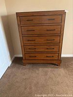 Front view of the solid wood dresser showing five drawers and black metal handles.