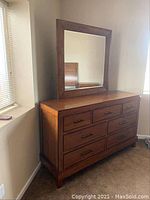 Front angled view of the dresser with mirror, showing wood finish, drawers, handles, and mirror frame.