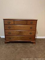 Front view of the solid wood 4-drawer antique-style dresser showing four drawers with brass handles and bracket feet.