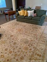Full view of a large 10x14 ft area rug placed under a sofa and table, showing its overall pattern and colors.