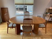 Dining table with four chairs arranged around it, pedestal base visible