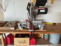 Front view of Craftsman miter saw on wooden workbench with pegboard backdrop