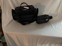 Sony Video8 camcorder displayed next to Ambico branded black carrying case on a white cloth background.