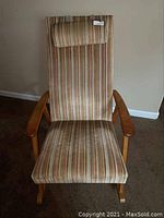 Front view of the mid-century modern rocking chair showing striped fabric upholstery and wooden armrests.