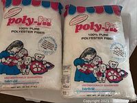 Two sealed bags of Poly-Fil polyester fiber, each weighing 16 oz, featuring colorful packaging and illustrations of a girl with stuffed animals.
