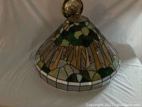 Side view of the Tiffany style stained glass lamp shade showing the floral and green leaf pattern, metal framing, and brass mounting hardware.