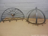 Two metal kitchen wall hanging racks; one semi-circular with a chicken motif and five hooks, the other dome-shaped with multiple hooks for pots and pans.