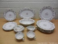 Photo showing full set of Noritake china including plates, cups, cream pitcher, sugar bowl, platters, and serving bowl arranged on table.