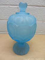 Front view of vintage blue frosted glass candy dish with lid, showing decorative embossed pattern and pedestal base