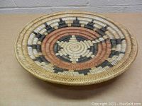 Top view showing full circular basket design, central star pattern with natural, black, and reddish-brown colors.