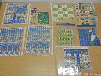 Photo showing multiple full sheets and several smaller groups of stamps on a table, including stamps featuring birds, butterflies, plants, and other themes.